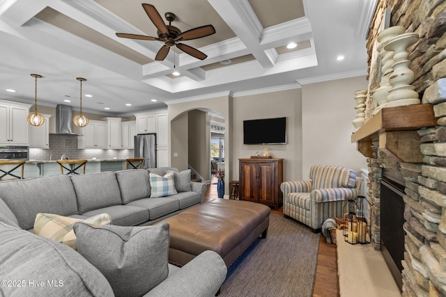 8549 Oak Abbey Trl NE, Leland, NC 28451 - living room with arched walkways, a stone fireplace, crown molding, and a ceiling fan