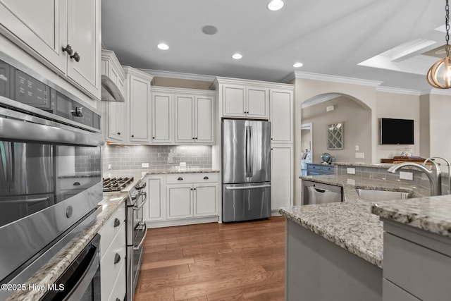 8549 Oak Abbey Trl NE, Leland, NC 28451 - kitchen featuring ornamental molding, a sink, arched walkways, appliances with stainless steel finishes, and white cabinetry