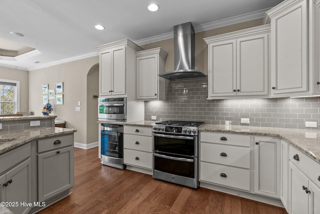 8549 Oak Abbey Trl NE, Leland, NC 28451 - kitchen with beverage cooler, stainless steel appliances, wall chimney range hood, arched walkways, and dark wood-type flooring