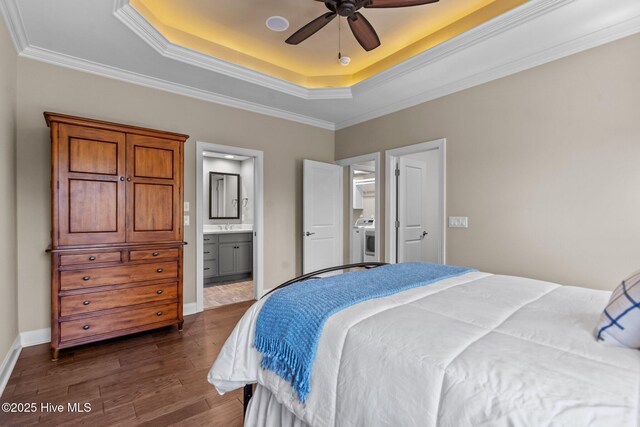 8549 Oak Abbey Trl NE, Leland, NC 28451 - bedroom featuring a tray ceiling, crown molding, connected bathroom, dark wood-type flooring, and washer / dryer