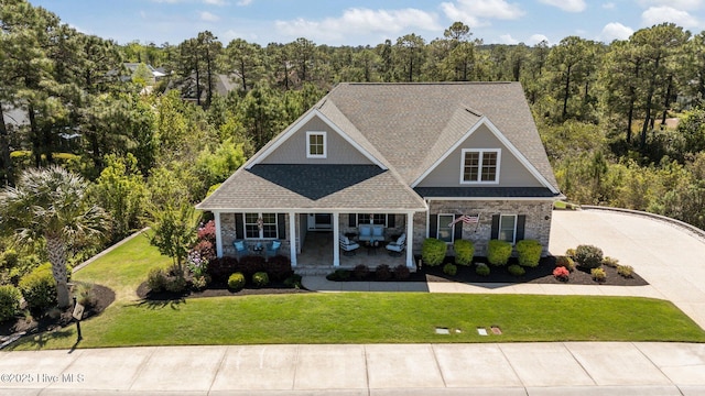 8549 Oak Abbey Trl NE, Leland, NC 28451 - craftsman-style house with roof with shingles, concrete driveway, a porch, a forest view, and a front yard