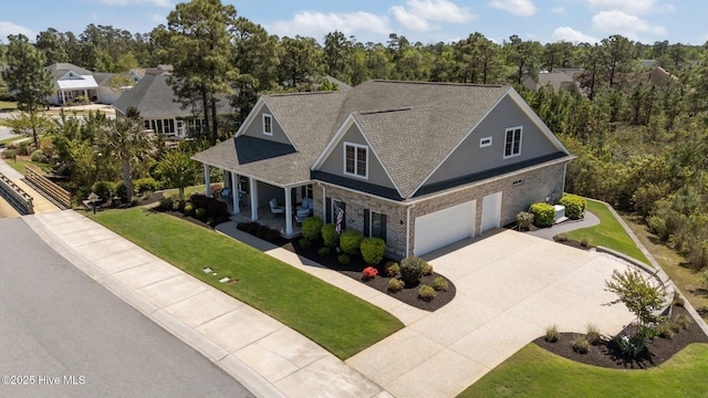 8549 Oak Abbey Trl NE, Leland, NC 28451 - view of front of home with a front lawn, stone siding, a porch, concrete driveway, and a garage