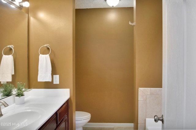 bathroom with toilet, vanity, baseboards, and a textured ceiling