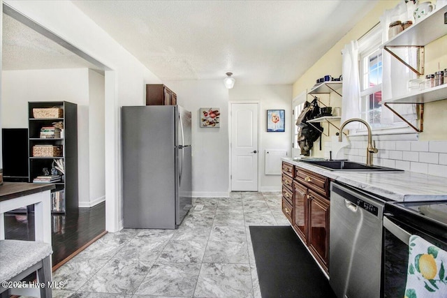 kitchen featuring tasteful backsplash, open shelves, light countertops, a sink, and stainless steel appliances