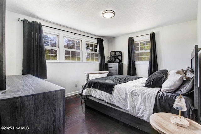 bedroom with baseboards, wood finished floors, and a textured ceiling