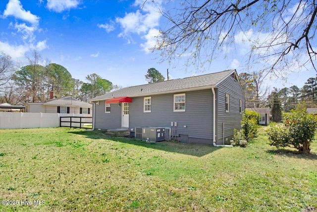 rear view of property featuring a yard, cooling unit, and fence