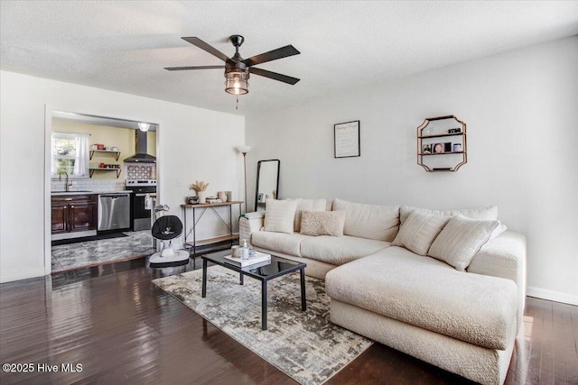 living room with dark wood-style flooring, ceiling fan, baseboards, and a textured ceiling