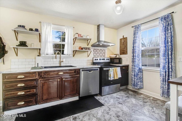 kitchen featuring tasteful backsplash, wall chimney range hood, open shelves, a sink, and stainless steel appliances