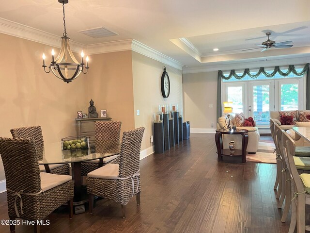 dining room featuring crown molding, a tray ceiling, visible vents, and dark wood-type flooring
