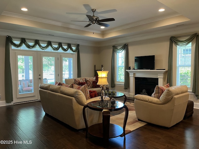 living room featuring a ceiling fan, a fireplace, dark wood-type flooring, and a wealth of natural light