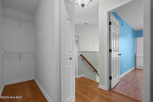 interior space with wood finished floors, visible vents, baseboards, and an upstairs landing