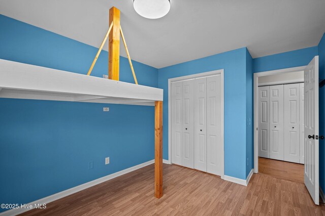 unfurnished bedroom featuring wood finished floors, baseboards, and a closet