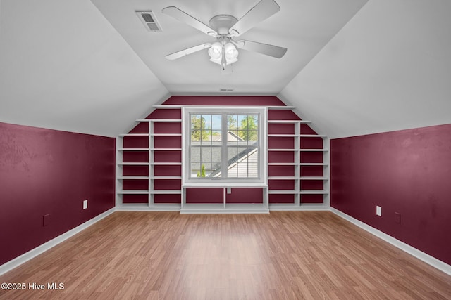additional living space featuring built in features, baseboards, visible vents, a ceiling fan, and wood finished floors