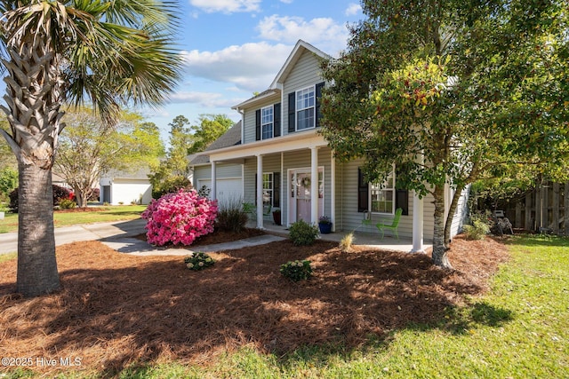 traditional-style home with a porch, driveway, fence, and an attached garage