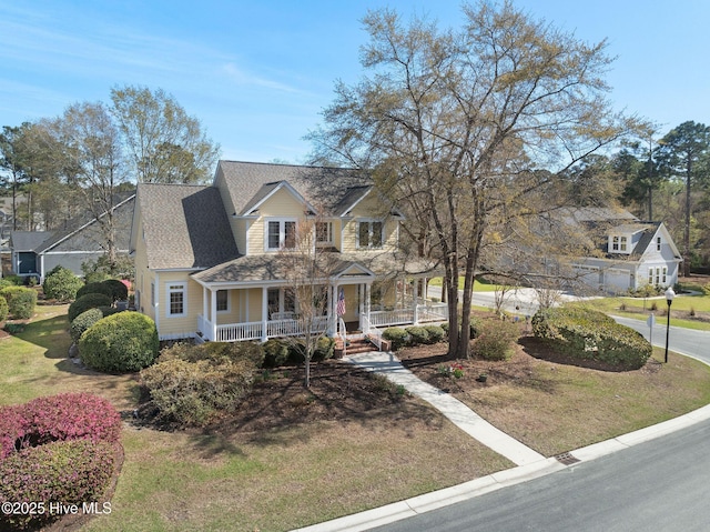 view of front facade featuring a front lawn, covered porch, and roof with shingles