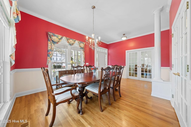 dining area featuring ornamental molding, french doors, ornate columns, and light wood-style floors