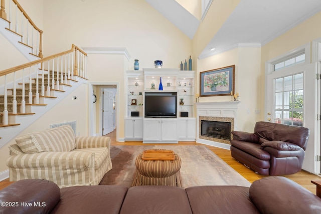 living room with high vaulted ceiling, light wood-type flooring, stairway, and a fireplace