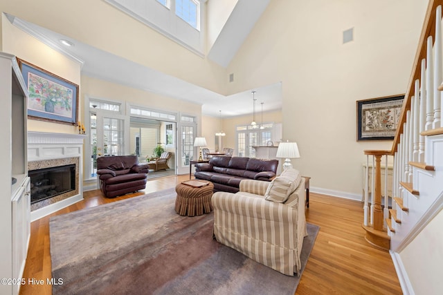 living area with baseboards, a fireplace, a towering ceiling, stairs, and wood finished floors