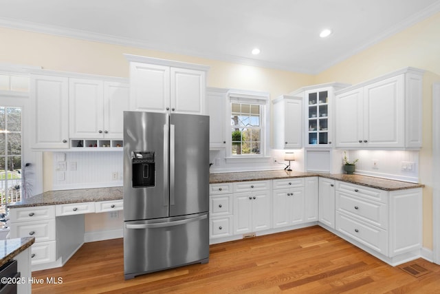 kitchen with stainless steel fridge with ice dispenser, white cabinets, visible vents, and dark stone counters