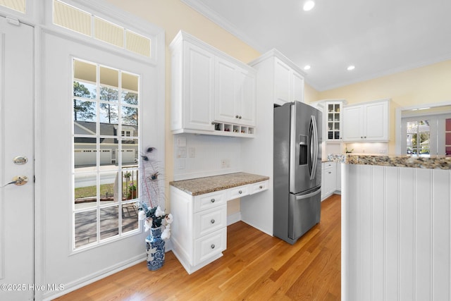 kitchen with stainless steel fridge with ice dispenser, built in study area, light wood-type flooring, and white cabinetry