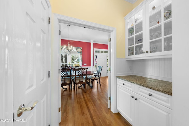 dining space with crown molding, wainscoting, a chandelier, and wood finished floors