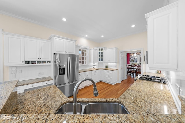 kitchen with plenty of natural light, a sink, light stone counters, and stainless steel fridge