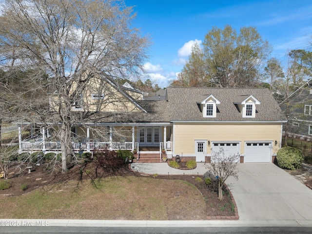 view of front of property featuring concrete driveway, roof with shingles, french doors, and covered porch