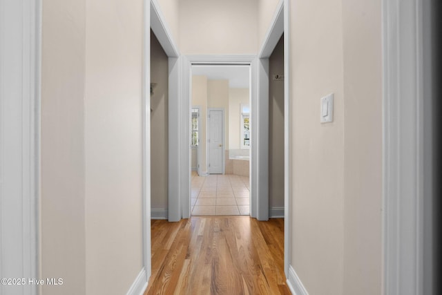 hall featuring baseboards and light wood finished floors
