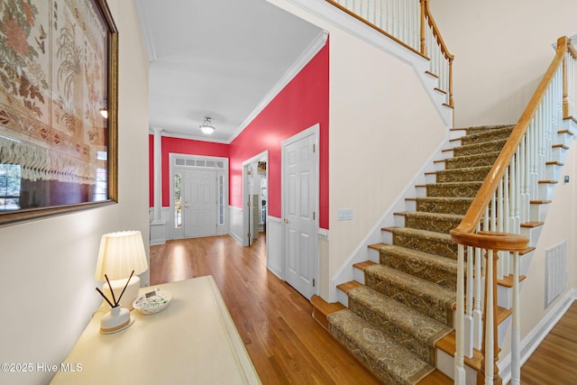 foyer featuring crown molding, visible vents, stairway, and wood finished floors