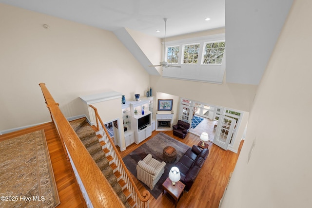 living room featuring a ceiling fan, a fireplace, recessed lighting, wood finished floors, and french doors