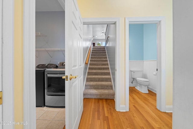 stairs with a wainscoted wall, independent washer and dryer, and wood finished floors