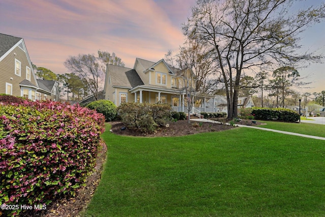 property exterior at dusk with a lawn and covered porch
