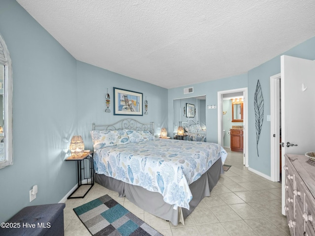 2000 New River Inlet Rd Unit 3513, North Topsail Beach, NC 28460 - bedroom with light tile patterned floors, a textured ceiling, ensuite bath, visible vents, and baseboards