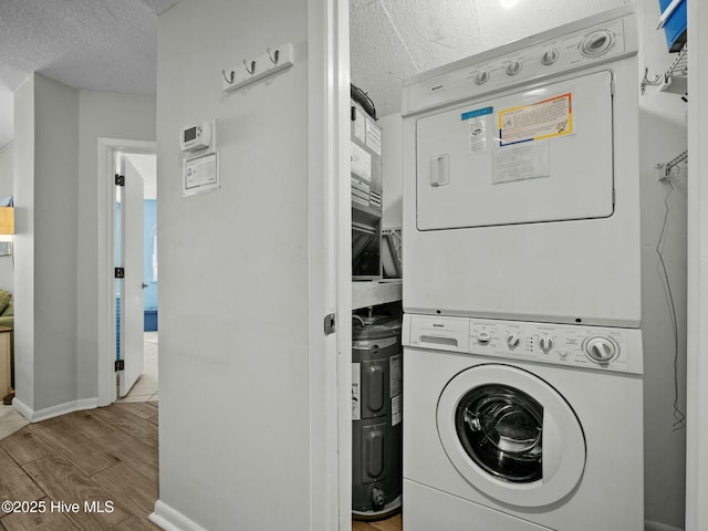 2000 New River Inlet Rd Unit 3513, North Topsail Beach, NC 28460 - washroom featuring baseboards, stacked washer and dryer, a textured ceiling, laundry area, and wood finished floors