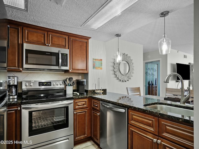 2000 New River Inlet Rd Unit 3513, North Topsail Beach, NC 28460 - kitchen with dark stone counters, appliances with stainless steel finishes, a sink, hanging light fixtures, and decorative backsplash