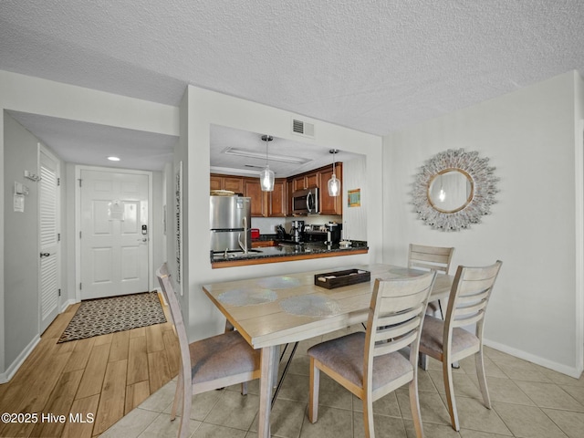 2000 New River Inlet Rd Unit 3513, North Topsail Beach, NC 28460 - dining room with light wood-type flooring, visible vents, a textured ceiling, and baseboards
