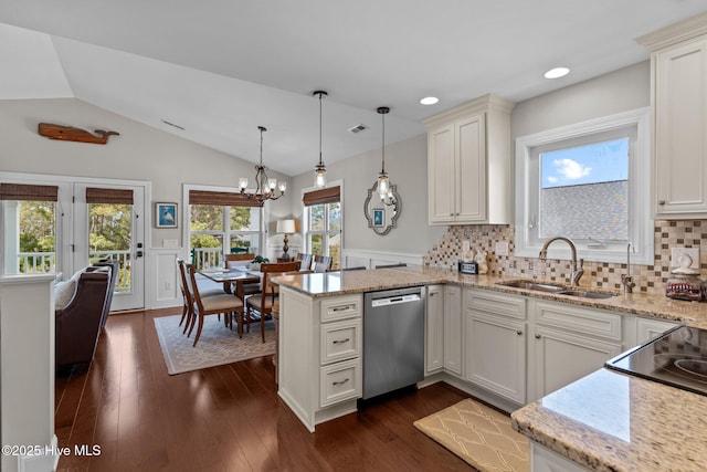 kitchen featuring a peninsula, dishwasher, a sink, wainscoting, and lofted ceiling