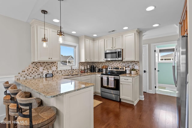 kitchen featuring visible vents, plenty of natural light, a sink, appliances with stainless steel finishes, and a peninsula