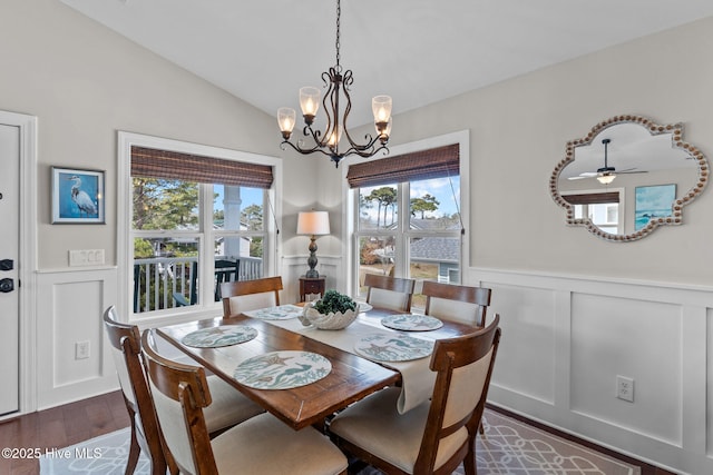 dining area with a decorative wall, dark wood-style floors, lofted ceiling, and a wainscoted wall