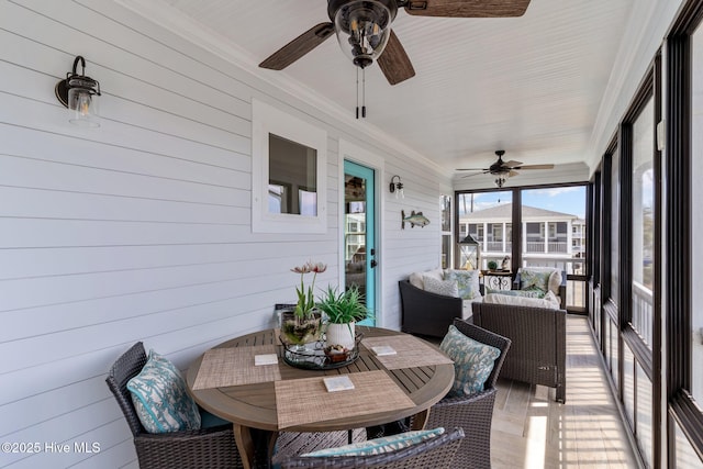 sunroom featuring outdoor dining area and a ceiling fan