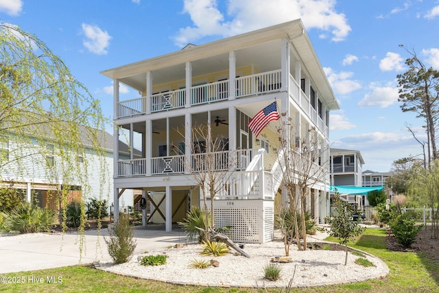 back of house featuring ceiling fan, stairway, a carport, a balcony, and concrete driveway