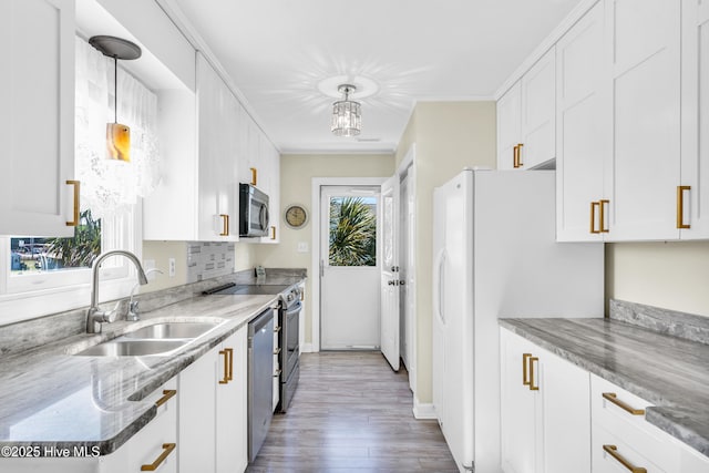 kitchen with white cabinetry, appliances with stainless steel finishes, a sink, and wood finished floors
