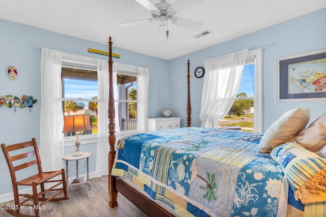 bedroom with baseboards, visible vents, multiple windows, and wood finished floors