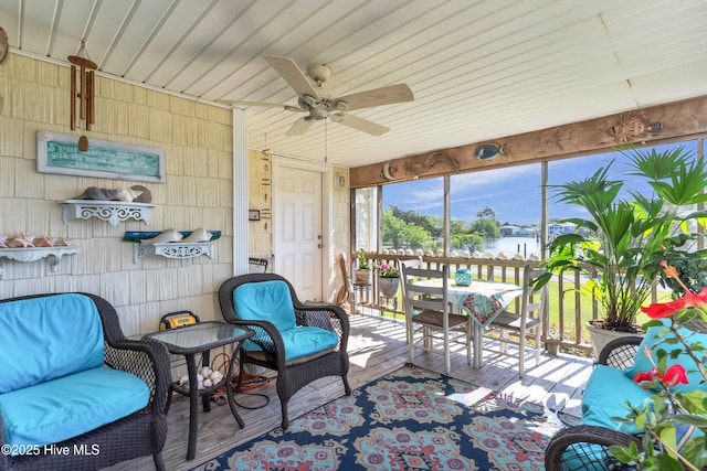 sunroom with a ceiling fan and a water view