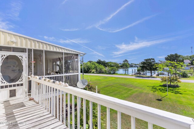 exterior space featuring a lawn, a water view, and a sunroom