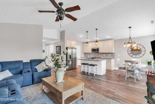 107 SW 25th St, Oak Island, NC 28465 - living area with baseboards, visible vents, ceiling fan with notable chandelier, vaulted ceiling, and light wood-style floors