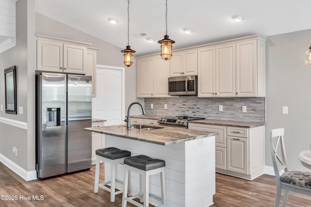 107 SW 25th St, Oak Island, NC 28465 - kitchen featuring light stone counters, a sink, wood finished floors, tasteful backsplash, and appliances with stainless steel finishes