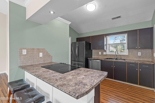 kitchen featuring a sink, a kitchen bar, dark wood-type flooring, visible vents, and appliances with stainless steel finishes