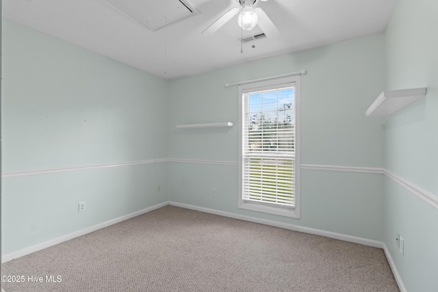 carpeted spare room featuring baseboards, visible vents, attic access, and ceiling fan