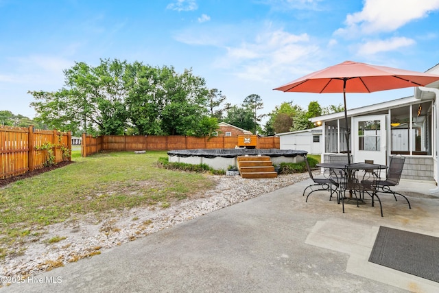 view of patio with a fenced backyard, outdoor dining area, a fenced in pool, and a sunroom